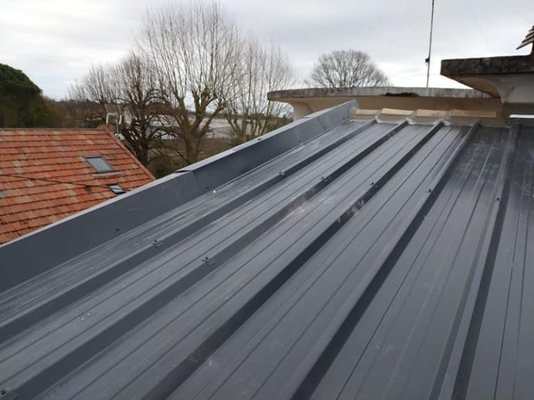 Installation de panneaux de toiture bac acier gris anthracite et pliages de rive métalliques.