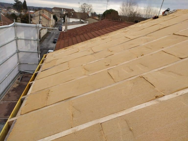 Panneaux d'isolant biosourcé posés entre des lattes de bois lors de la rénovation thermique d'un toit incliné.