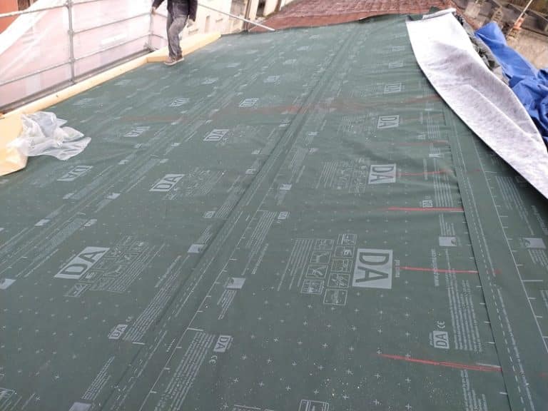 Installation d'une membrane d'étanchéité Pro Clima DA sur un toit en rénovation avec échafaudage.